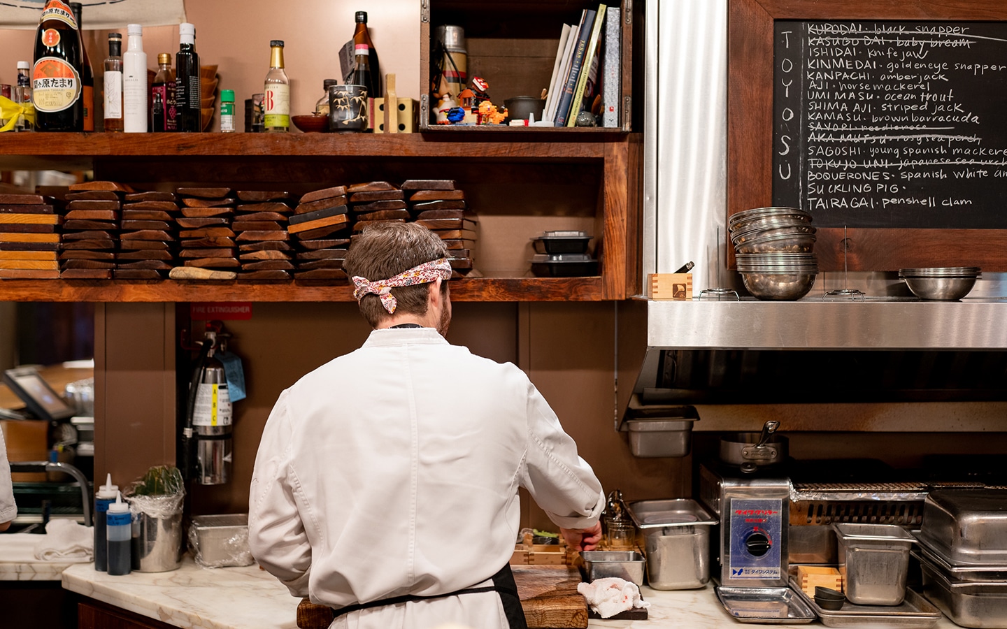 A chef in a kitchen preparing food for a private dining event.